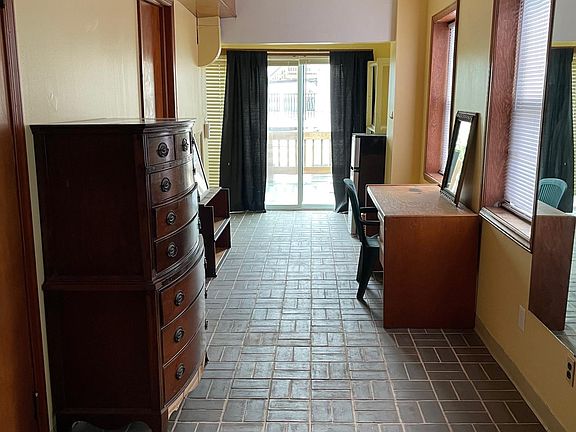 This space narrows as the bathroom and 2 closets take up some of the footprint. The floor is quarry tile. Large wall mounted mirror opposite the tall boy dresser. Sliding glass door faces south.