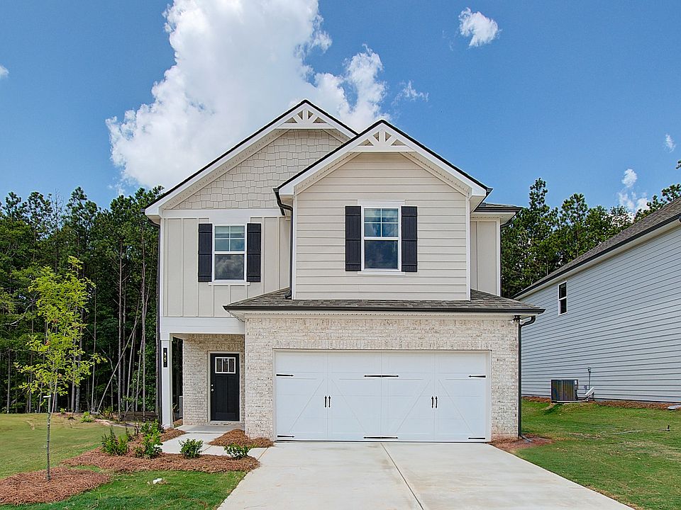 Two-story home in Conyers, GA with gray siding, brick facade accents, prominent windows, and an atta