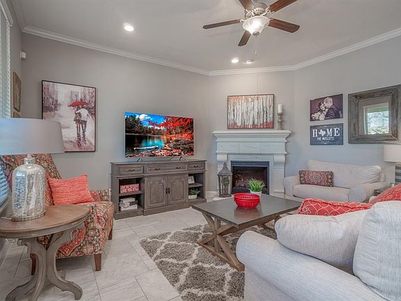 Travertine tile, a large fireplace, crown molding, neutral paint and large windows with a view to the backyard all make this the perfect living area.