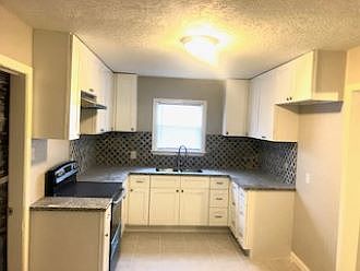 Renovated kitchen with tile floor, new cabinets, granite counter tops, new range.