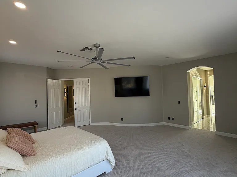 Spacious primary suite featuring a wall-mounted TV and direct access to the ensuite bathroom