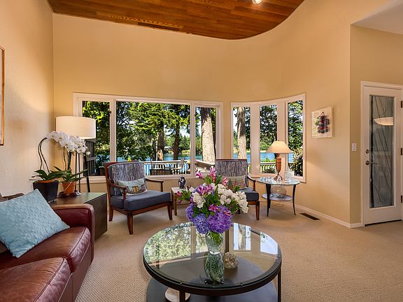 The Living Room has tall windows with water views across the water. The door to the right leads to the expansive deck.