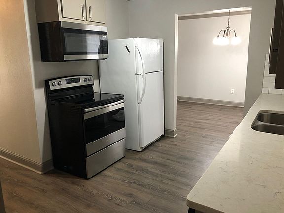 Kitchen with refrigerator, stove & microware with vent and light above stove.