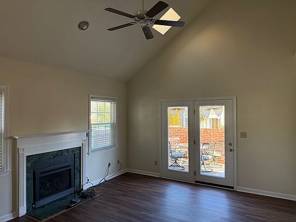 Living room with gas fireplace, patio door entrance, ceiling fan, and sky lights.