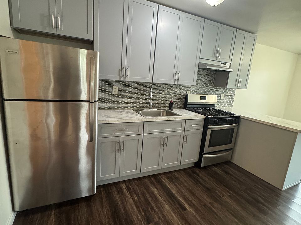 Renovated kitchen featuring modern gray cabinetry, marble-style countertops, and stainless steel appliances. Plenty of cabinet space for storage and everyday cooking.