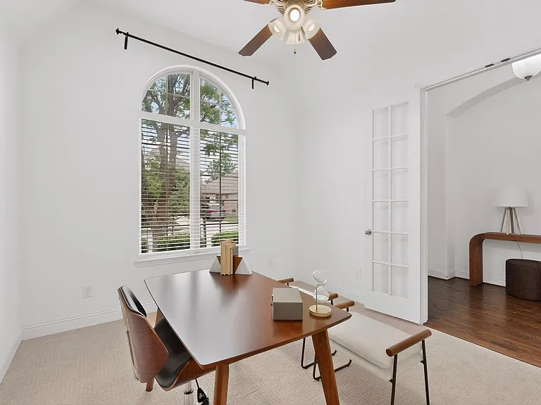Bright office with a ceiling fan and a tall window overlooking the front yard