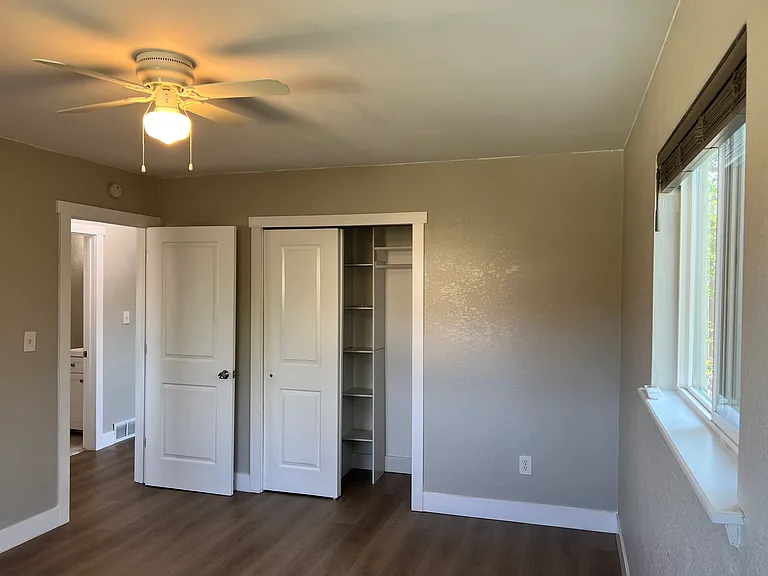Primary bedroom features a custom closet organization system to maximize storage, plus a cooling ceiling fan.