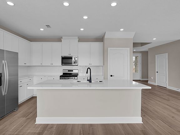 The spacious kitchen island serves as a perfect use for meal preparation or casual seating.