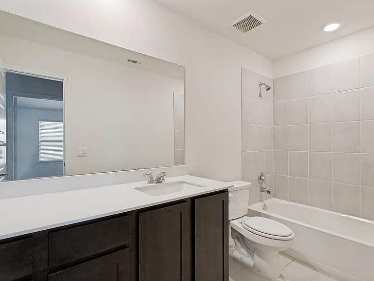Bathroom featuring a single vanity with dark wood-finish cabinetry, a white countertop, and a large wall-mounted mirror