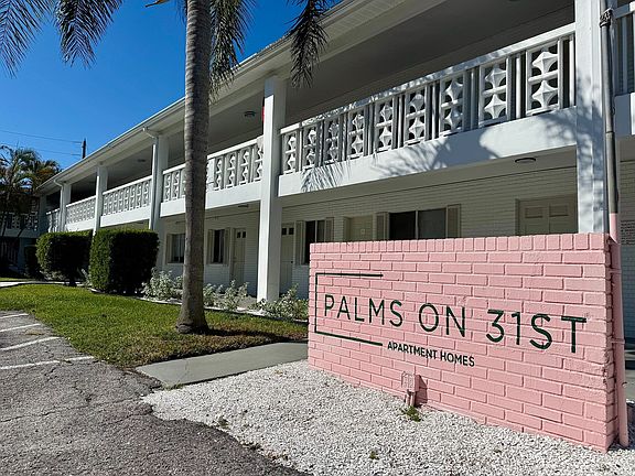 Charming two-story apartment building with unique lattice balcony design and lush palm surroundings at Palms on 31st.