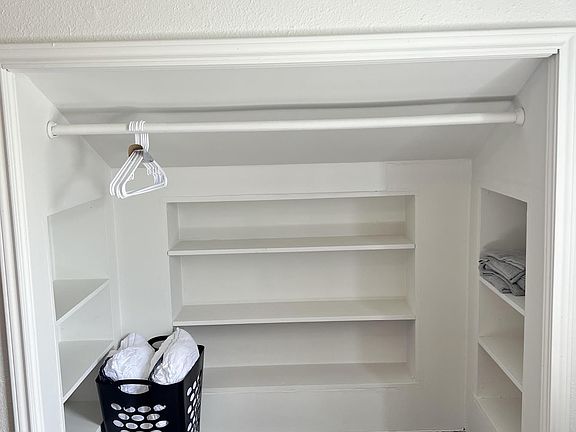Built-in closet storage with hanging rod and multiple shelving sections for clothing, linens, and personal items.