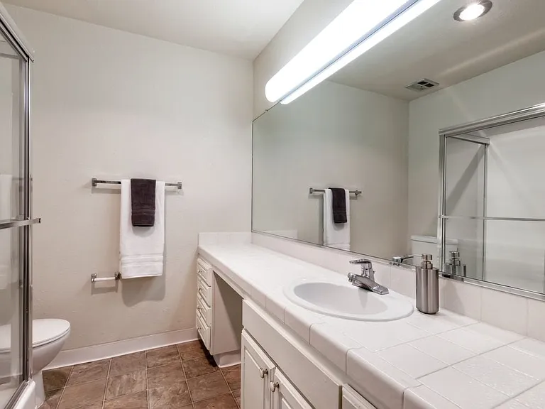 Classic Package I bath with white tile countertop, white cabinetry, and vinyl flooring (select homes)