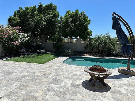 Backyard with pool, travertine deck, and artificial turf. Desert landscaping, large shade trees.