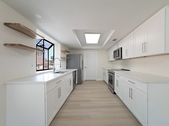 Kitchen with beautiful casement window over sink, electric stove, microwave, and fridge. Pantry door shown at end of kitchen.