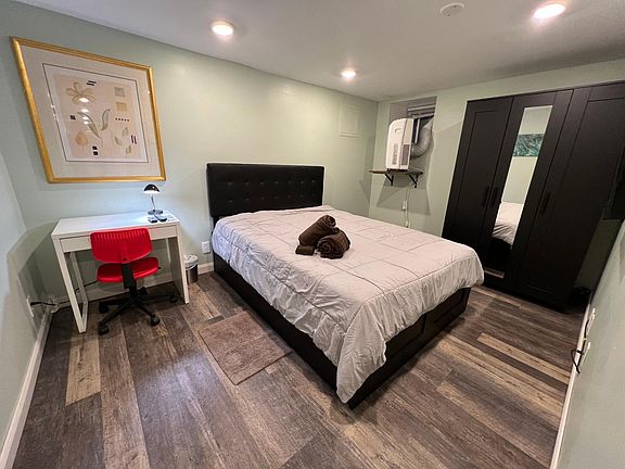 First Bedroom. Completely furnished with queen storage bed with four drawers, armoire with shelves and hanger, desk and mod red office chair. On right wall just out of view is flat screen TV on the wall with wifi and 200 cable channels.