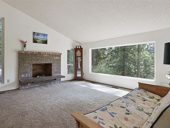 Living room with large picture windows, dramatic vaulted ceiling and cozy wood burning fireplace. Look at the serene views. 