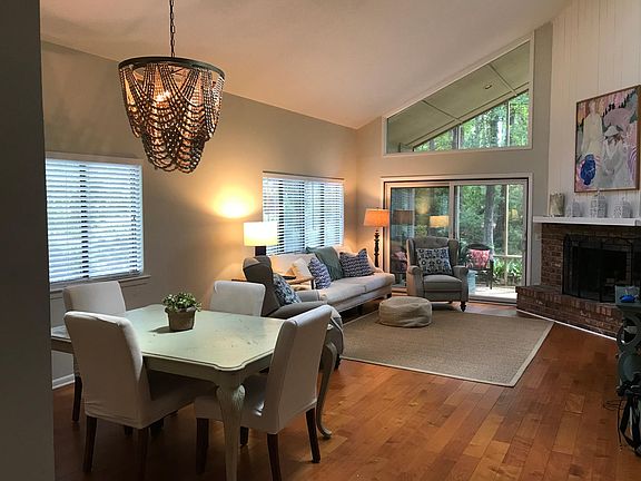 Open living/dining area with wood burning fireplace leading out to screened in porch.