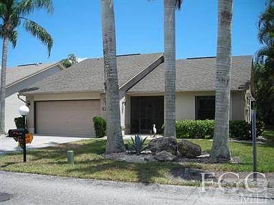 Front view single family 2 car garage and tropical landscaping.