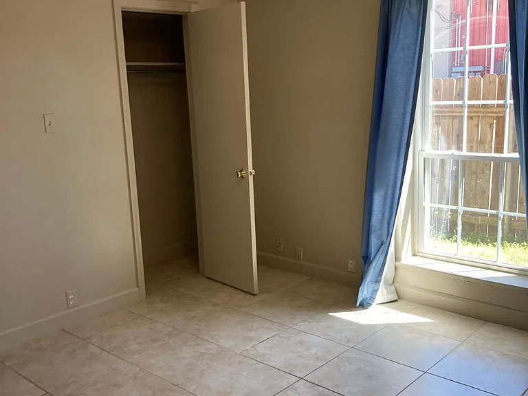 Sunny second bedroom overlooking the fenced patio and yard, offering natural light and a pleasant view of the home's private outdoor space.
