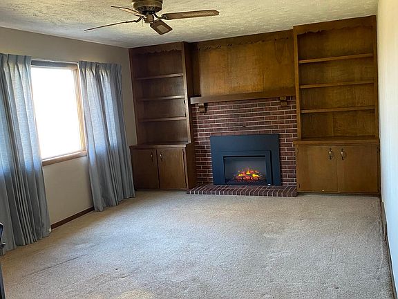 Living room with built-in bookcases and electric fireplace insert.