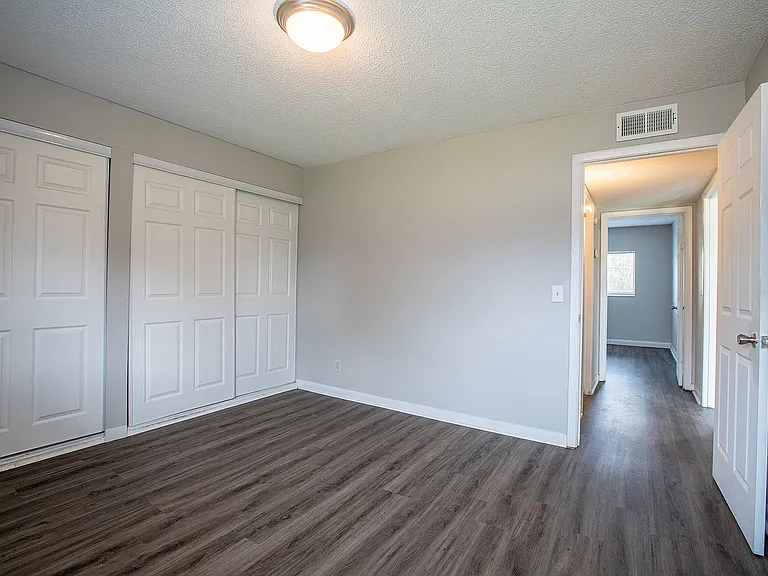Spacious bedroom with elegant wood flooring, ample closet space, and soft natural lighting.