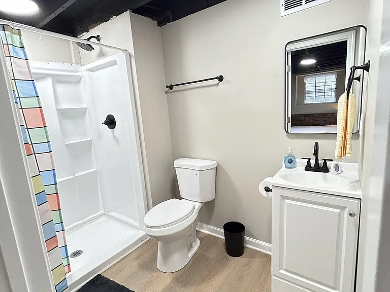 Full bathroom with walk-in shower, vanity with storage, and durable plank-style flooring for easy everyday upkeep.