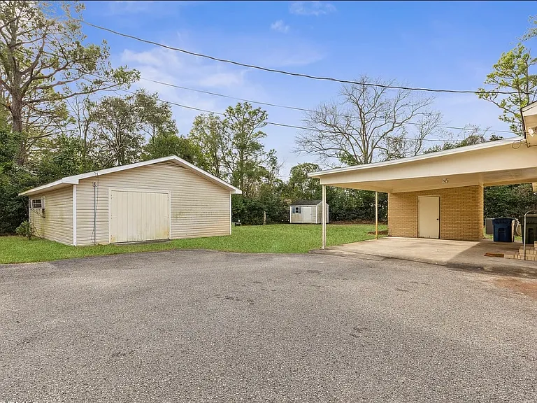 Back yard, car port, outbuilding, and shed.