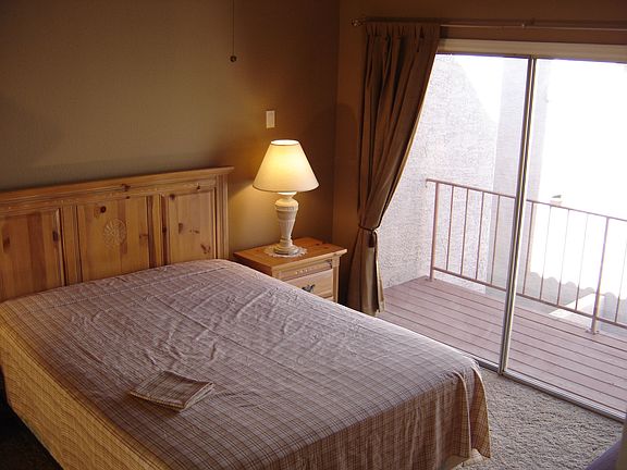 Large master bedroom with vaulted ceilings & a private deck.