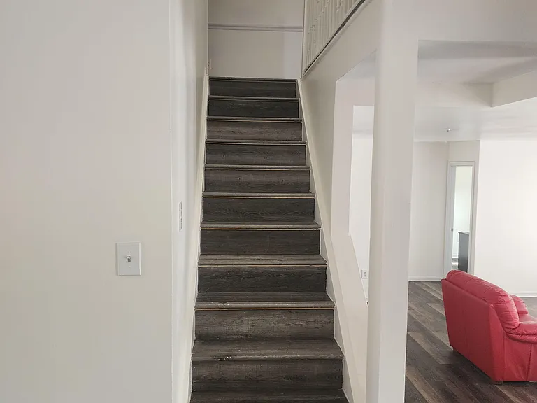 Interior staircase with dark wood-look flooring and open sightlines to the adjacent living area for easy circulation.