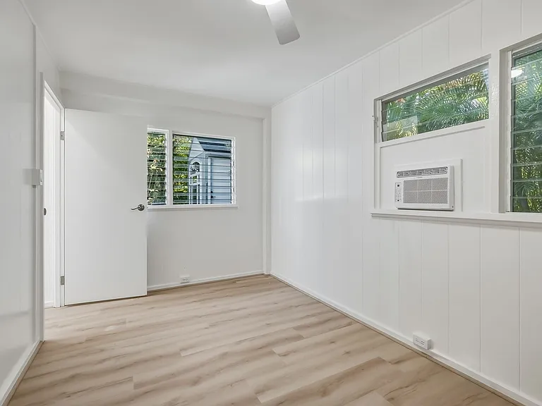 The bedroom has lots of windows and a window unit AC.