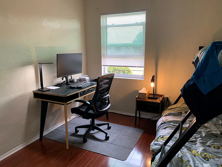 An office desk with all amenities in the second bedroom with the bunk bed and a nightstand.