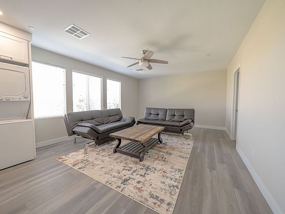 A bright living space furnished with sleek couches and a coffee table, complemented by large windows that invite natural light, enhancing the room's airy feel.