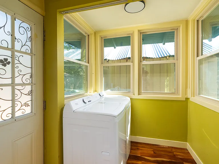 Bright laundry nook with natural light and modern washer. Conveniently located near the back door, this cheerful space makes everyday chores easy and pleasant.