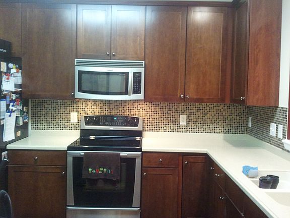 Kitchen w/ SS Appliances, Corian Countertops & Sink and Tiled Backsplash