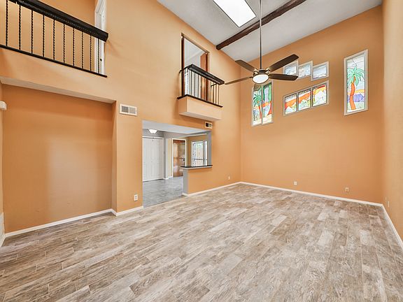 Living room with high vaulted ceiling, large fan and unique stained glass windows