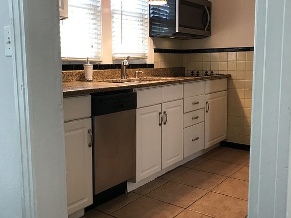 Kitchen features granite countertops, pendant accent lighting, and easy clean white cabinets.
