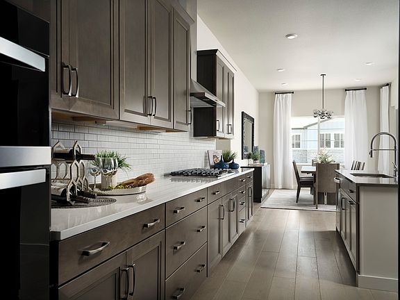 A modern, sleek kitchen with dark gray cabinets, white countertops, and stainless steel appliances,