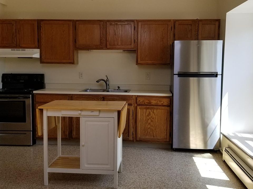 Kitchen includes stove, refrigerator, and moveable prep table.