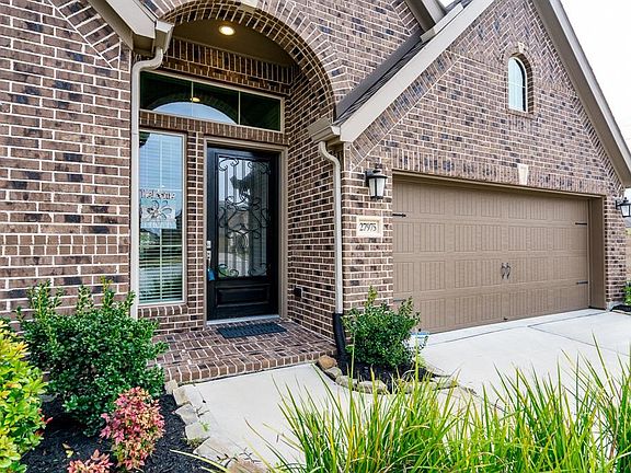 A curved sidewalk leads you to a covered arched porch and a pretty wrought iron and glass door that beckons you to enter the home!