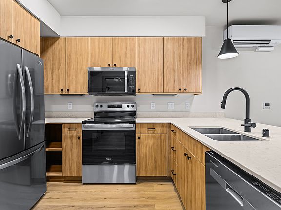 Modern kitchen with sleek stainless steel appliances, elegant wood cabinetry, and stylish black fixtures. Modern kitchen with sleek stainless steel appliances, elegant wood cabinetry, and stylish black fixtures.
