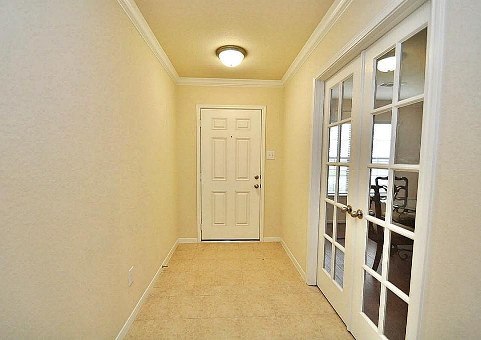 Enter to crown molding and large neutral tile flooring