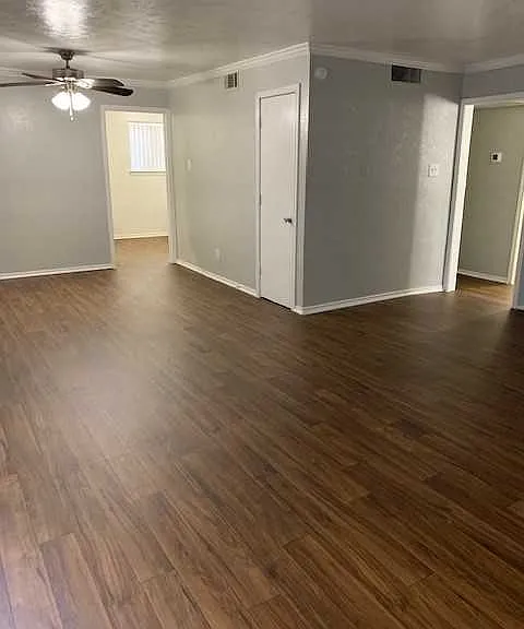 Spacious bedroom with wood-style flooring, large windows, and ample natural light.