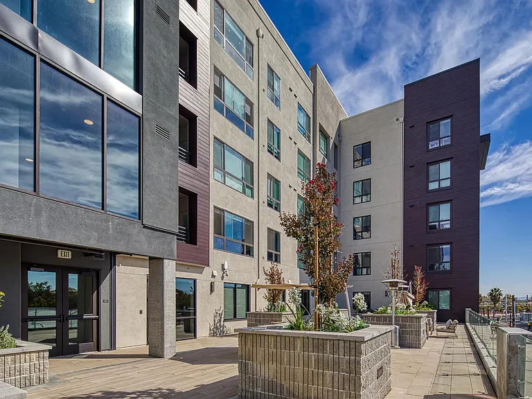 Outdoor terrace with raised planters, modern facades, and open_air seating creating a bright community gathering space.