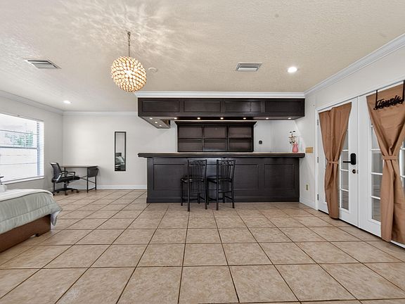 Spacious multipurpose room with a built-in bar, tile flooring, and French doors for easy access and entertaining.
