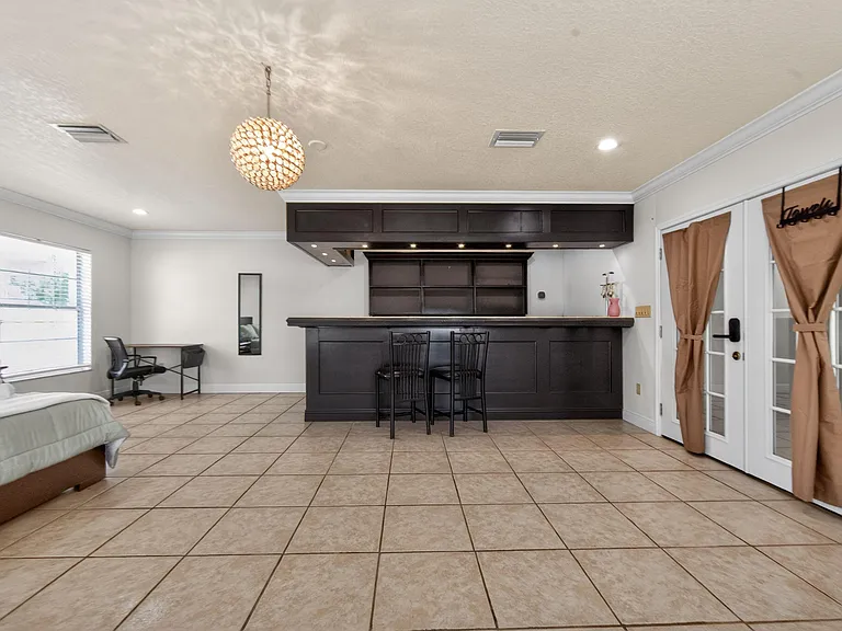 Spacious multipurpose room with a built-in bar, tile flooring, and French doors for easy access and entertaining.