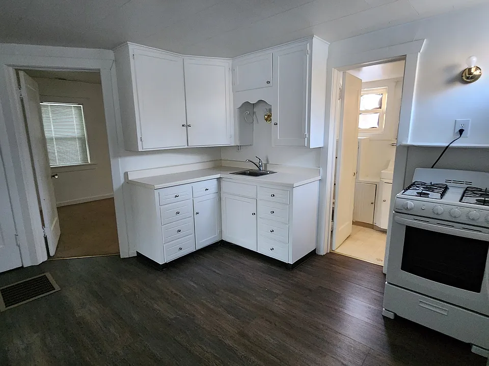 Kitchen picture taken from the corner where the kitchen table would sit. It looks into the open doors of the bathroom and bedroom.
There carpet on bedroom floor and linoleum in bathroom and vinyl tile in kitchen.