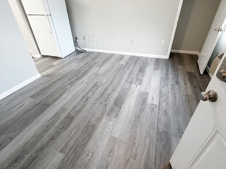 Alternate angle of the bright bedroom, emphasizing the clean, freshly painted walls, classic white doors, and sleek new LVP flooring.