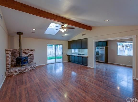 Open living room with cozy wood burning stove and brick surround.