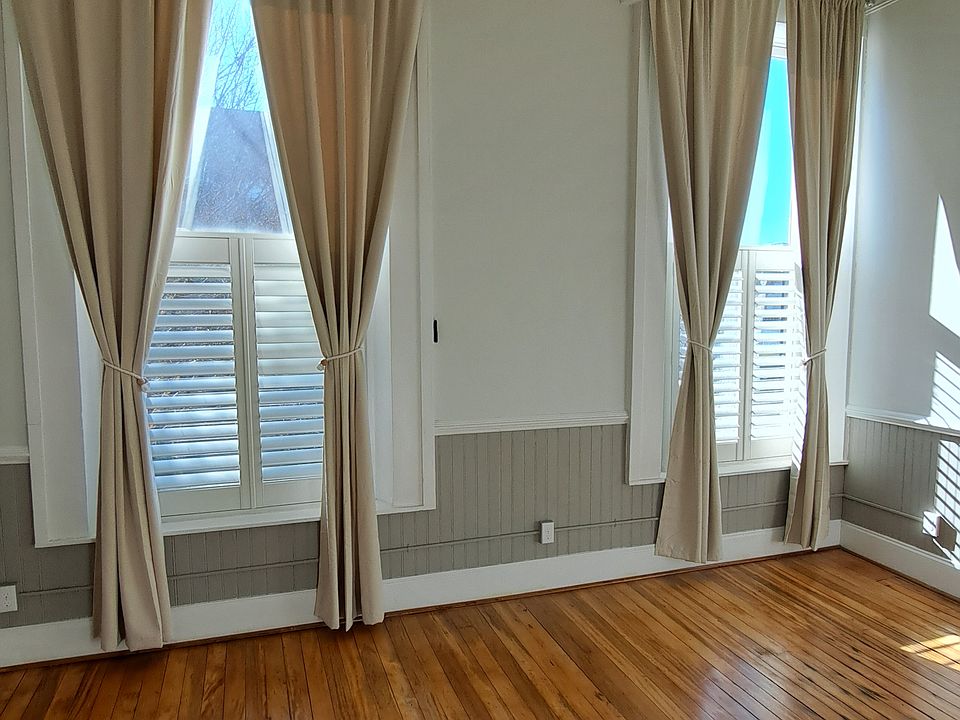 Photo of bedroom with oversized windows, plantation shutters, and privacy curtains.
