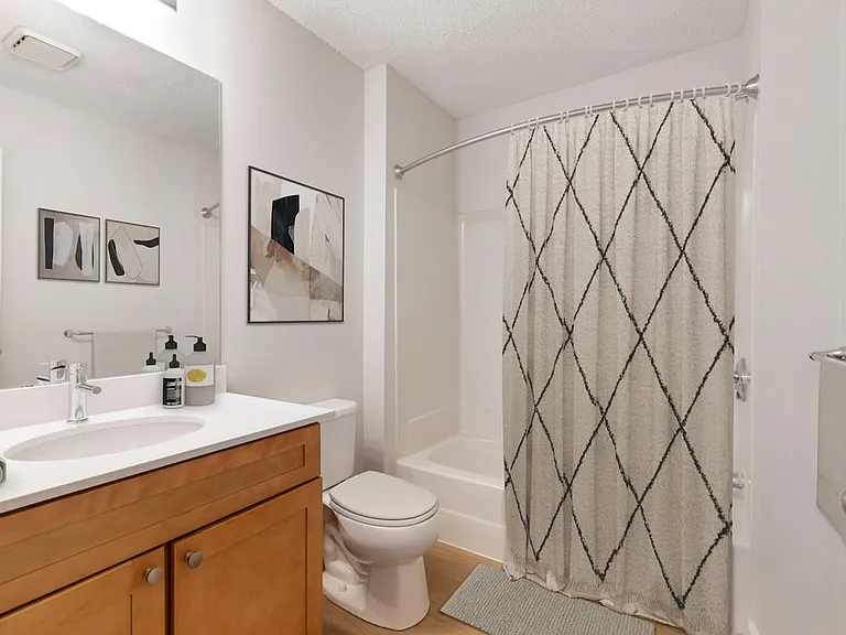 Renovated Package I bath with white quartz countertops, maple cabinetry, and hard surface flooring